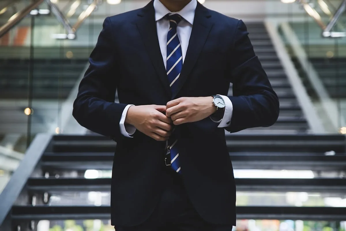 An IT consultant in a dark suit on the steps of an office building