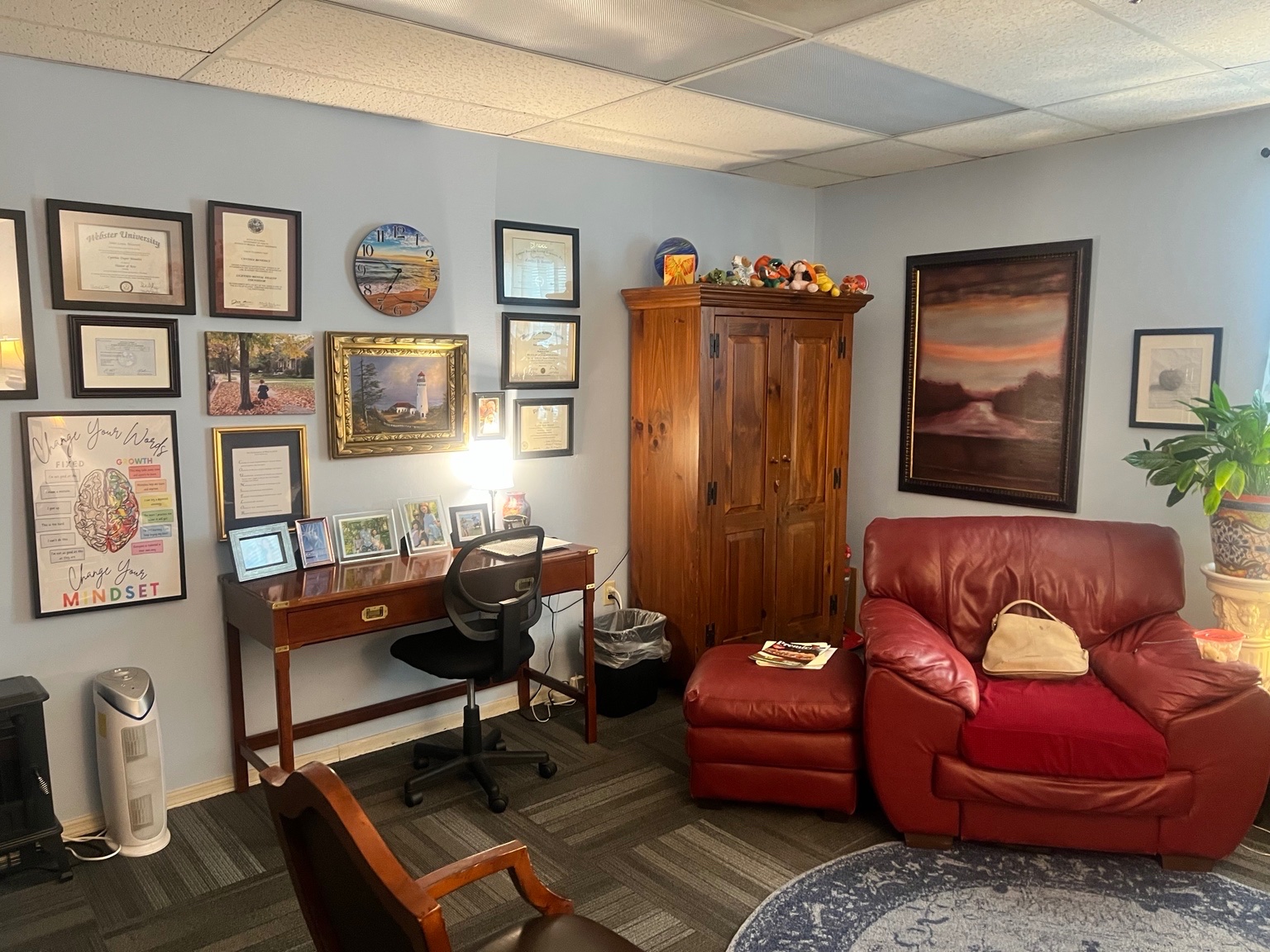 Wall of framed degrees and licenses in Cynthia Benedict's Longwood counseling office