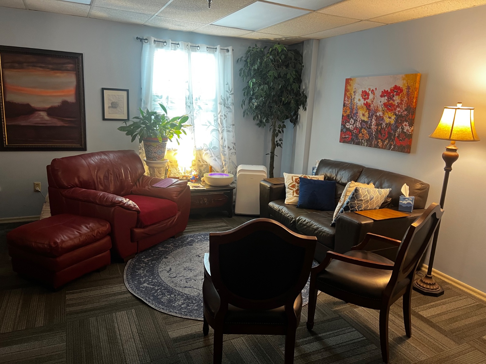 Cynthia Benedict's Longwood counseling office with leather seating, a round rug, floor lamp and bookshelf
