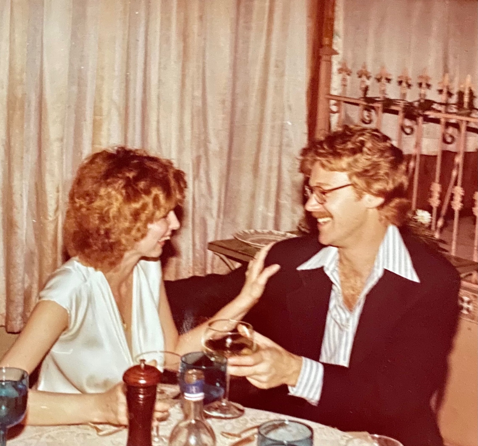 A couple laughing together over dinner at a candlelit table