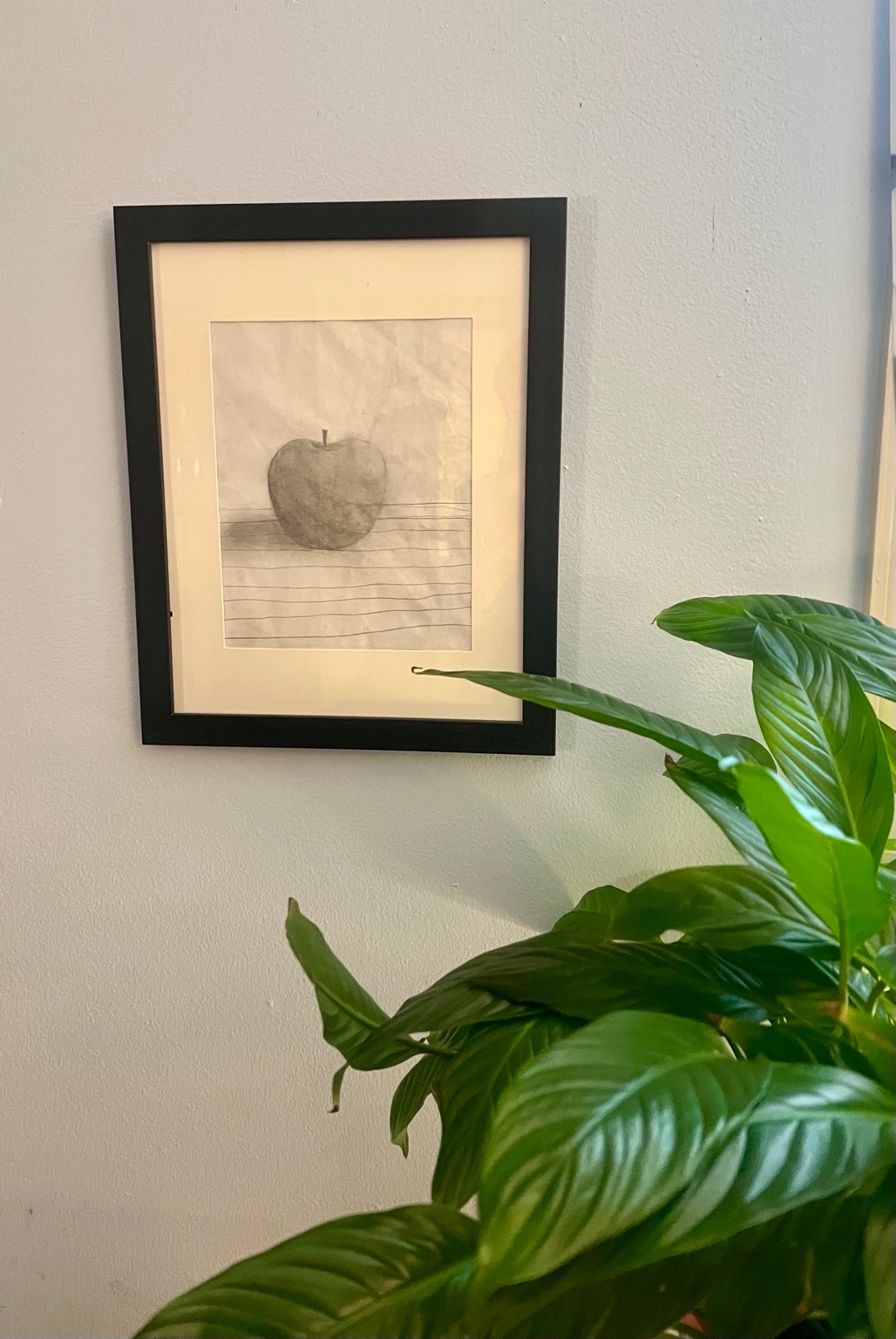 Framed pencil drawing of an apple, artwork by Cynthia's granddaughter, displayed on her office wall